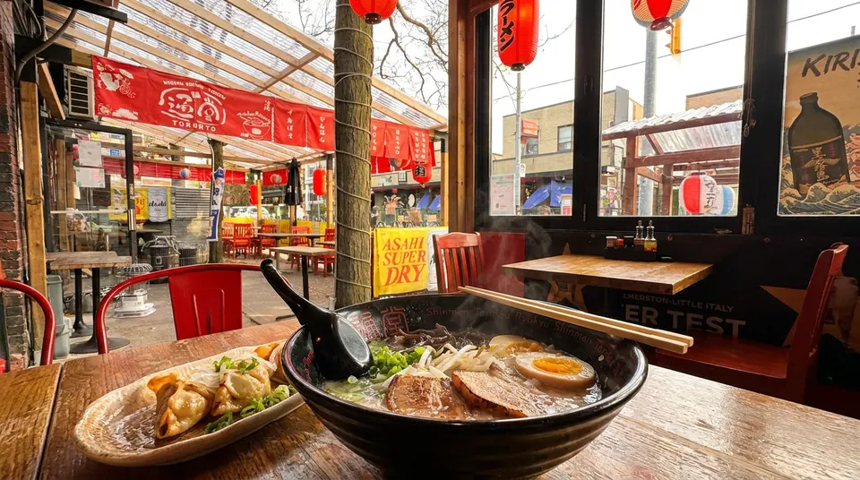 A steaming bowl of ramen and crispy gyoza served on a wooden table overlooking a covered patio.