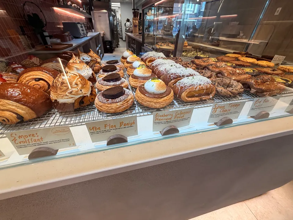 A display case filled with various pastries including croissants, danishes with meringue toppings, and chocolate-filled pastries at Bakerrae bakery.