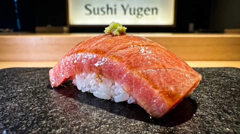 A single piece of premium otoro nigiri sushi topped with a dab of fresh wasabi, served on a textured dark stone plate at Sushi Yugen.