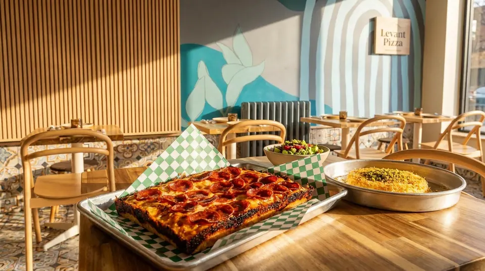 Freshly baked thick-crust pepperoni pizza and sides on a wooden table at Levant Pizza.
