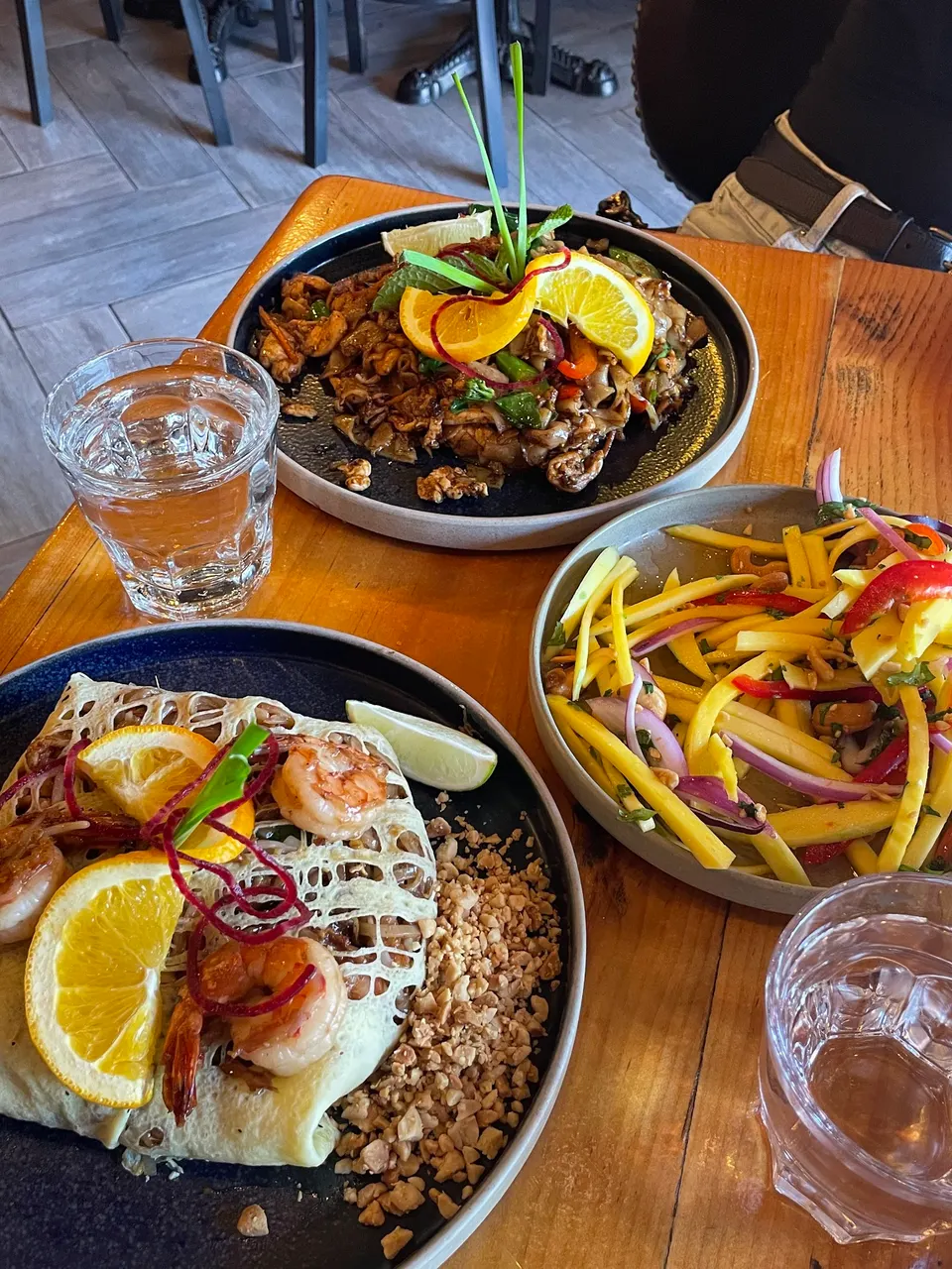A colorful spread of Thai dishes including Pad Thai, stir-fried noodles, and mango salad at Imm Thai Kitchen.