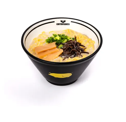 A bowl of ramen with yellow noodles, bamboo shoots, wood ear mushrooms, and chopped green onions in a creamy broth, served in a black bowl with a gold pig logo.