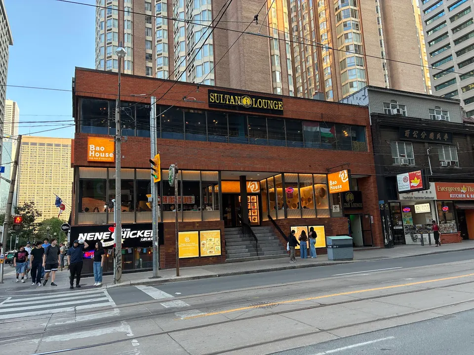 Exterior view of Bao House on Dundas Street, a two-story brick building with large windows, signage, and people walking on the sidewalk in front.