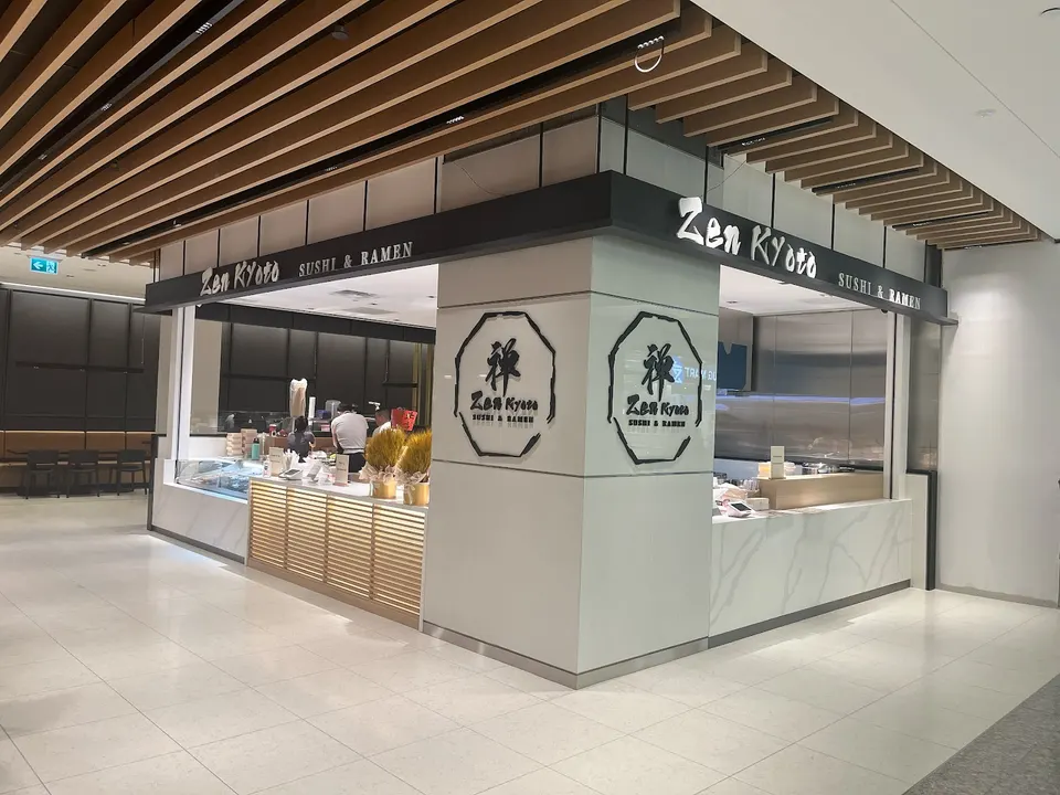 The storefront of Zen Kyoto Sushi & Ramen in the Bay Adelaide Centre, featuring a modern white counter, light wood paneling, and black signage with white lettering.
