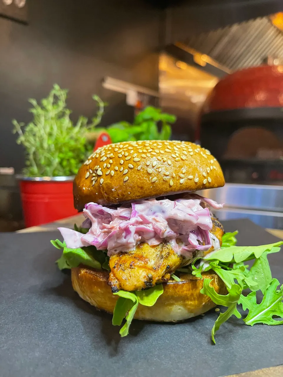 A freshly prepared grilled chicken burger with creamy coleslaw and fresh arugula at Zula Burger & Pizza.