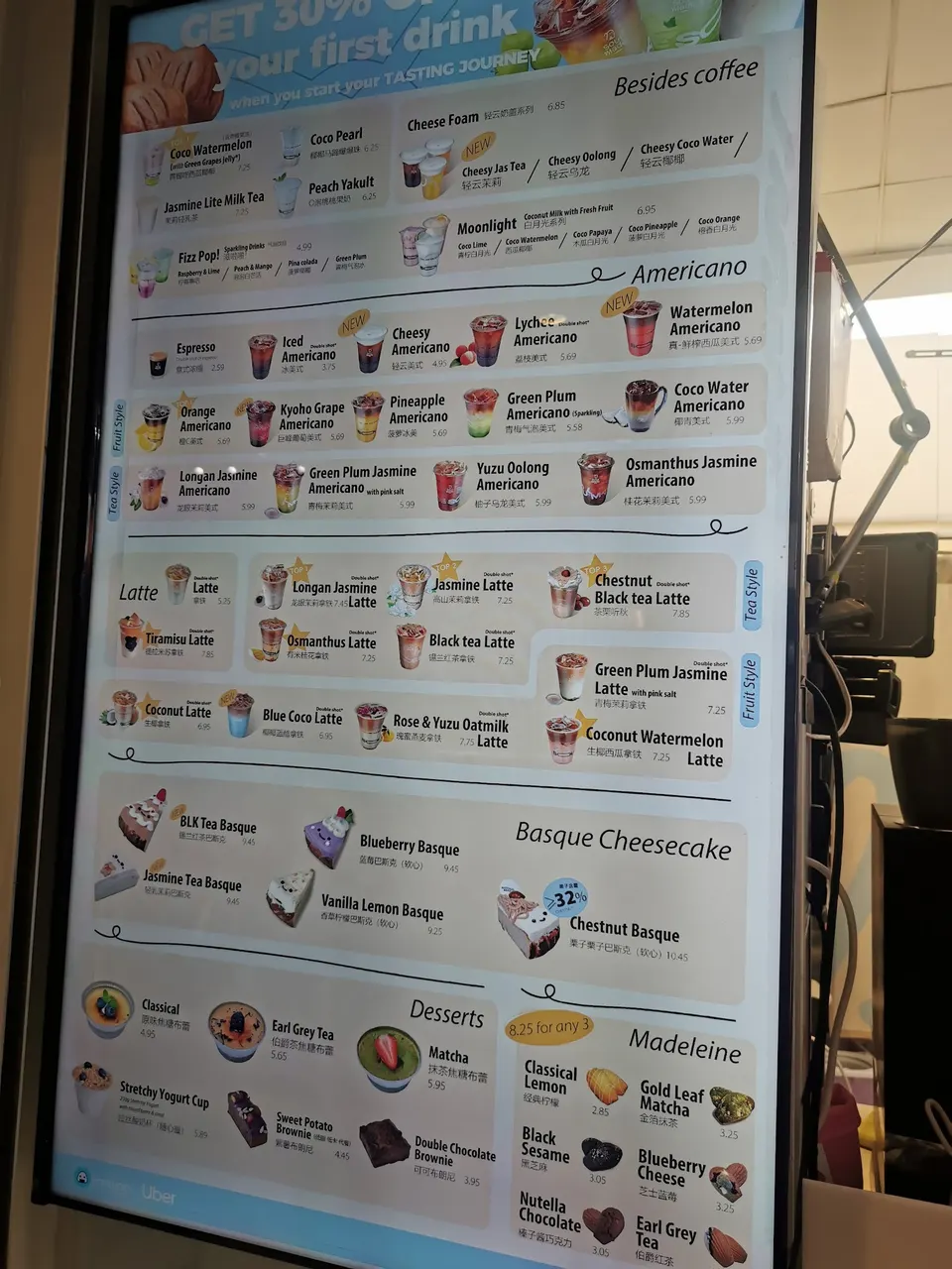 A digital menu board for Soul Made Cafe displaying a wide selection of drinks and desserts, including Americano variations, lattes, Basque cheesecakes, and madeleines.